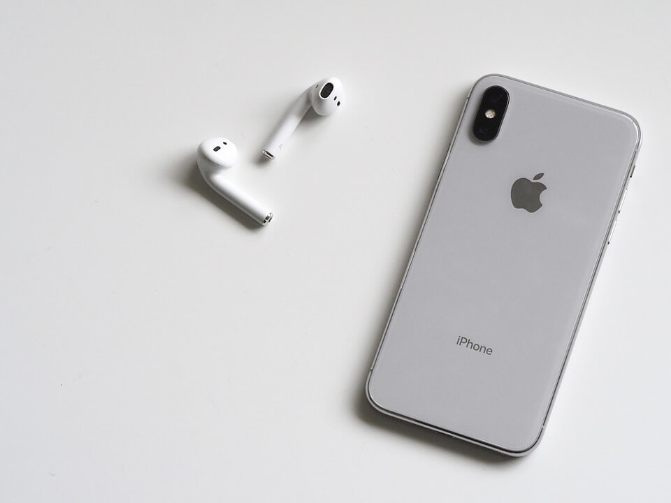 iphone x branco em cima da mesa e fones de ouvido sem fio iphone-x-e-fones-sem-fio