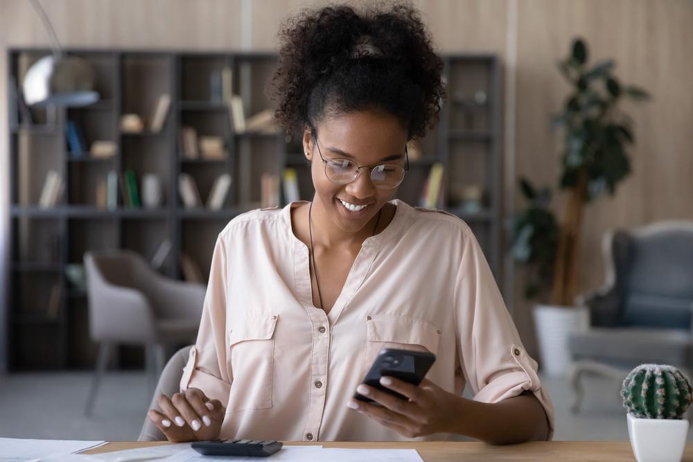 Mulher olhando para seu smartphone enquanto sorri.
