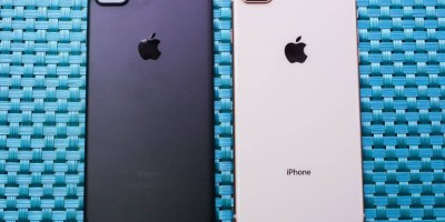 Foto de 2 iPhones 8 Plus com a parte traseira para cima, dispostos em uma superfície de fibra entrelaçada na cor azul. O aparelho da esquerda é da cor cinza-espacial, enquanto o da direita é prateado.