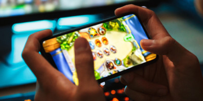 Mãos segurando um smartphone gamer, com o visor mostrando o jogo.