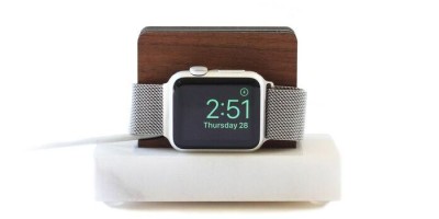 Smartwatch sobre uma base de madeira com fundo branco.