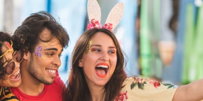 Cuidados no carnaval 2020: Duas mulheres e um homem, fantasiados para o carnaval, tirando selfie em uma rua.