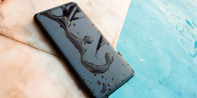 Um celular está na beira da piscina com água em sua tela
